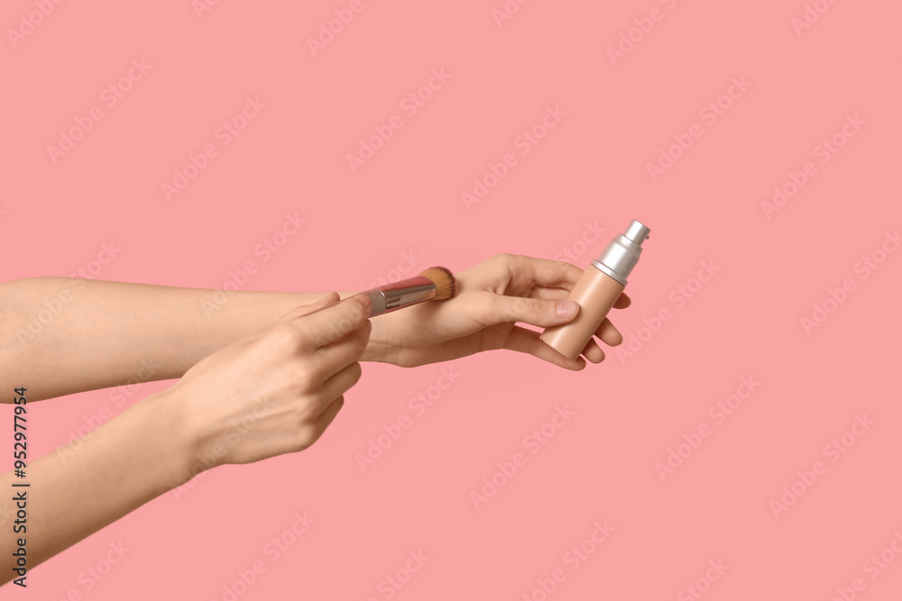 Female hands with bottle of makeup foundation and brush on pink background Female hands with bottle of makeup foundation and brush on pink background