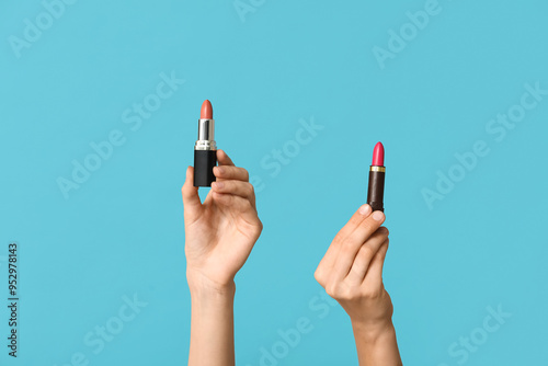 Female hands with different lipsticks on blue background