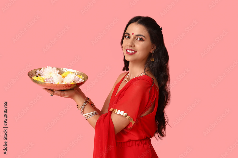 Beautiful young happy Indian woman in sari holding plate with candles and flowers on pink background. Divaly celebration Beautiful young happy Indian woman in sari holding plate with candles and flowers on pink background. Divaly celebration