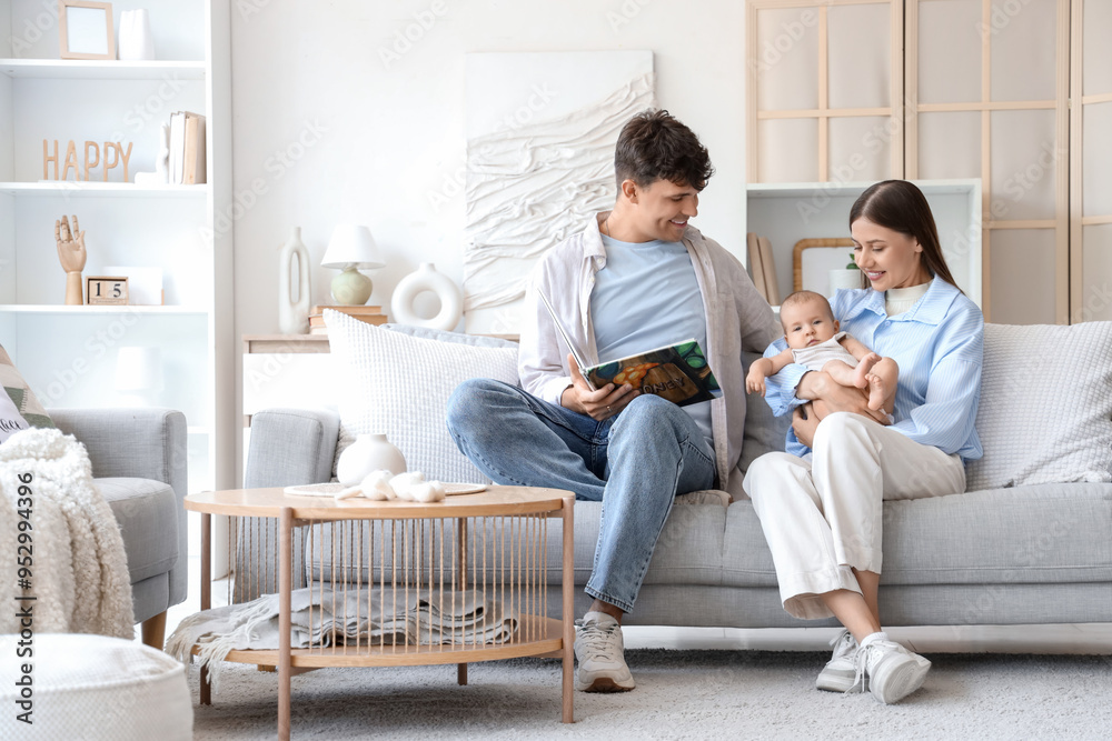 Young parents with their little baby reading book on sofa at home Young parents with their little baby reading book on sofa at home