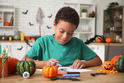 Teenage African-American boy drawing Halloween picture at table photo