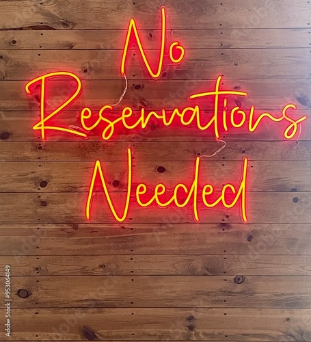 Bright neon No Reservations Needed sign is displayed inside a restaurant.