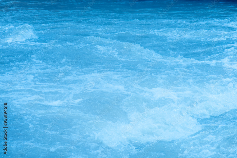 Obraz premium Blue water with ripples on the surface. Defocus blurred transparent blue colored clear calm water surface texture with splashes and bubbles. Water waves with shining pattern texture background.