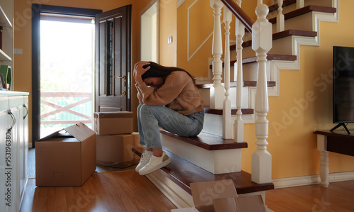 Fotografie Divorced woman sitting on the stairs of her home, looking sad and exhausted