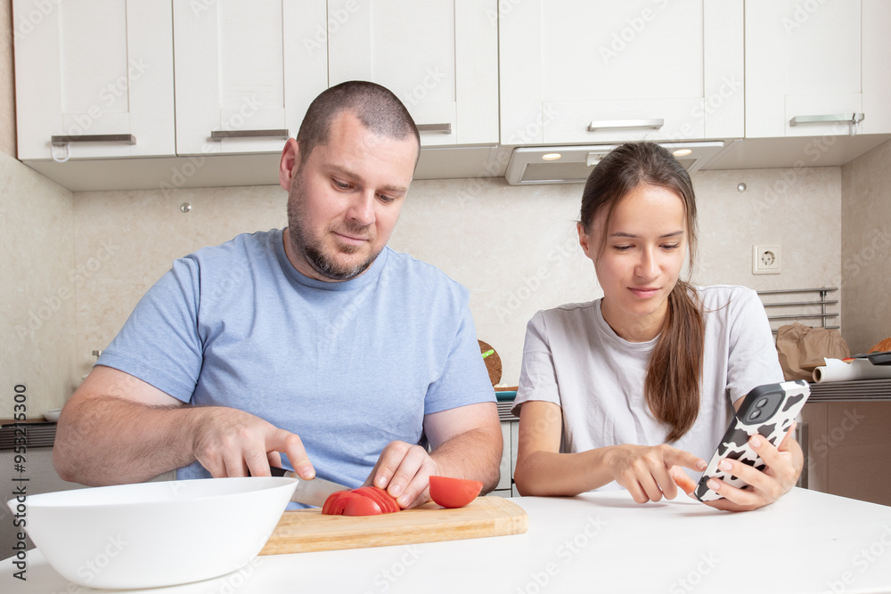 Teenage girl and father cook using a recipe on phone, food preparation with a mobile, enhancing family togetherness and joy. Teenage girl and father cook using a recipe on phone, food preparation with a mobile, enhancing family togetherness and joy.