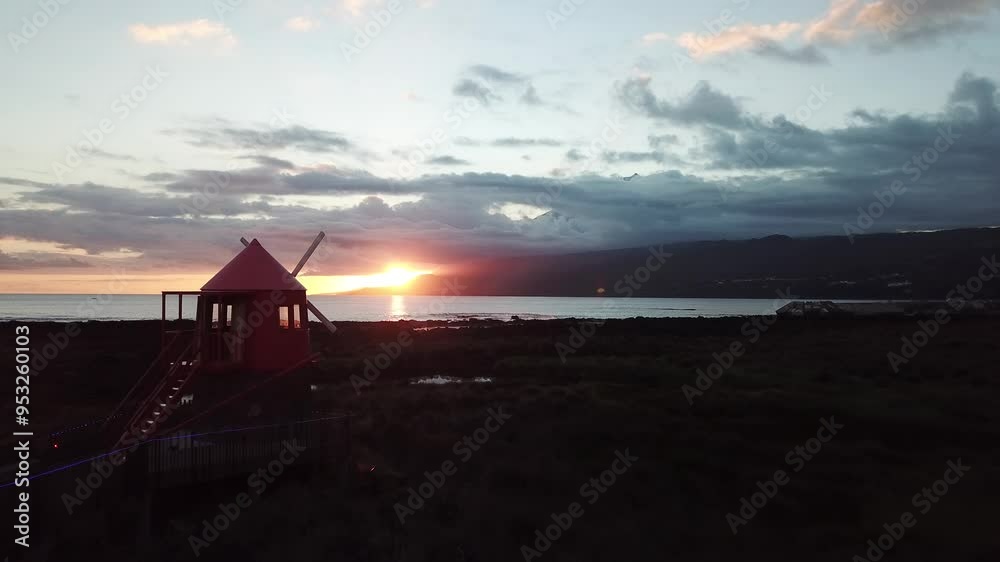 Coucher de soleil sur le mont Pico aux Açores , et le moulin rouge du village de Lajes
