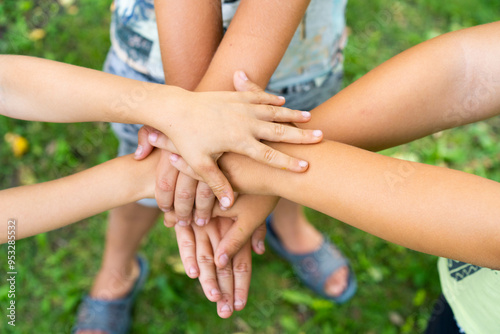 children holding hands standing on the green grass, the concept of friendship and a group of young people working in a team