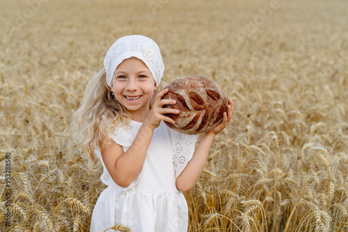 Little beautiful blonde girl with rye bread in a field of ears of rye