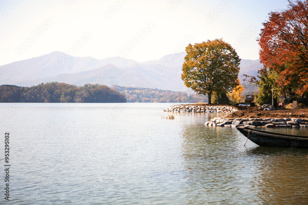 Fototapeta premium tranquil landscape at the lakeside with a wooden boat in autumn