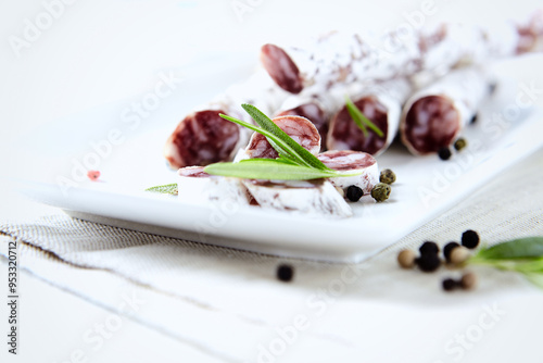 Obraz na plátně Sliced french salami with fresh rosemary on white background