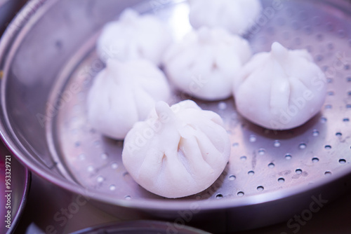 Maharashtrian sweet of Modak that is offered to Lord Ganesh, garnished with kesar (saffron) to be had with Ghee bowl and Lord Ganpati in the background. photo