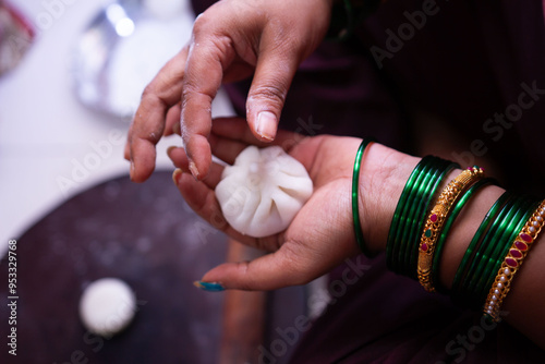 Woman making sweet rice modak stuffed with grated coconut and jaggery