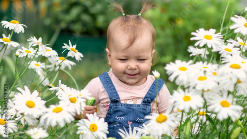 Little girl smelling chamomile flowers. Selective focus.