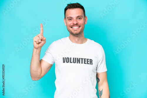 Young volunteer caucasian man isolated on blue background pointing up a great idea