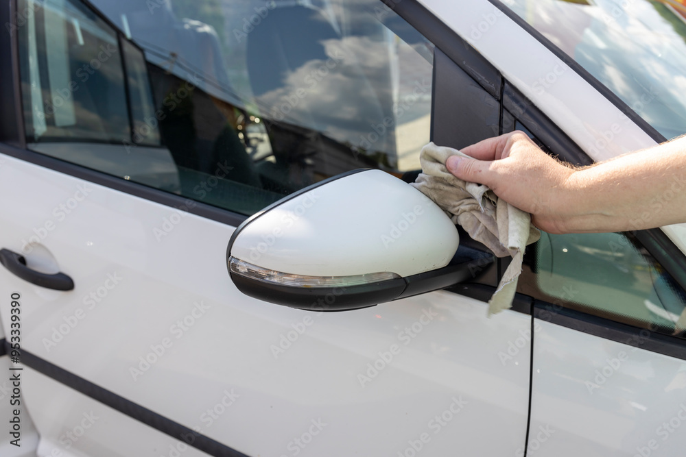 A person is wiping a car mirror with a cloth A person is wiping a car mirror with a cloth