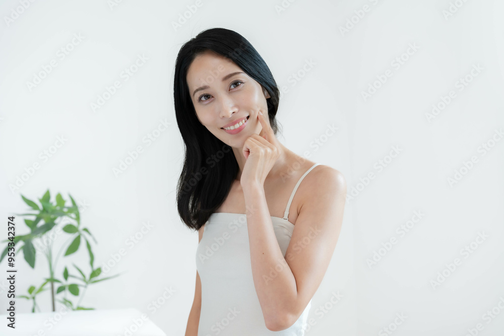 頬に手を当て微笑むキャミソールを着た女性 頬に手を当て微笑むキャミソールを着た女性