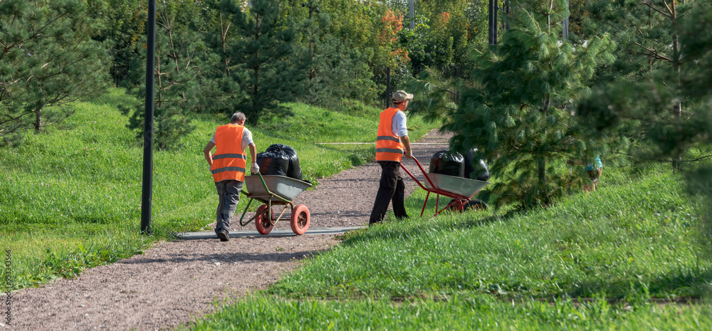 Two men are pushing wheelbarrows down a path Two men are pushing wheelbarrows down a path