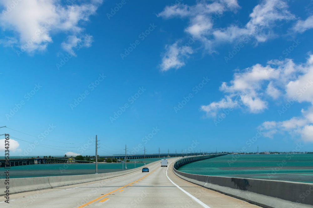 Fototapeta premium Drivers’ perspective over the Seven Mile Bridge or Florida State Road A1A towards Key West, FL, USA and cars on the road with on left side the Old Seven Mile Bridge