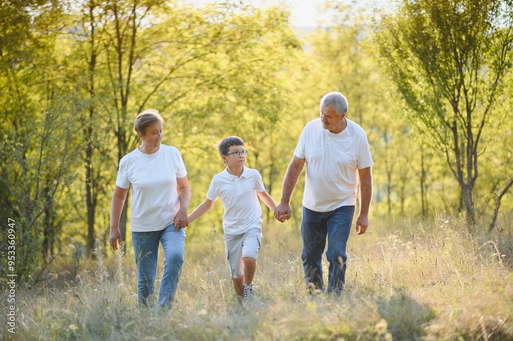 Grandson, grandfather and grandmother sitting on grass having fun outdoors in park at sunset Grandson, grandfather and grandmother sitting on grass having fun outdoors in park at sunset