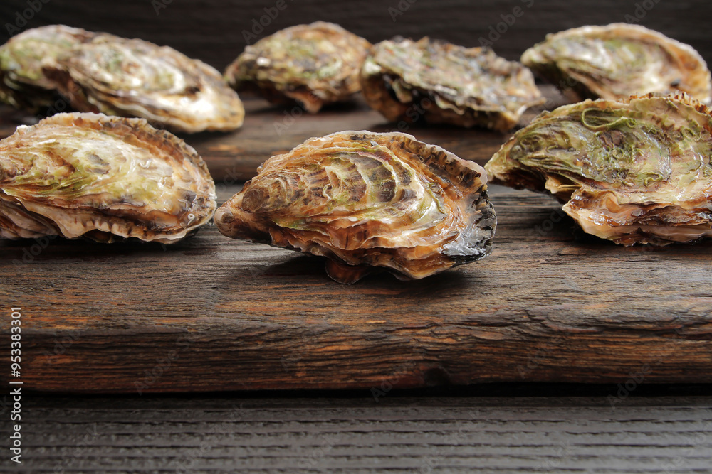 Concept, women's happiness and men's health. Fresh sea oysters on a dark wooden background. Open bivalve oysters, with mother-of-pearl pearls. Concept, women's happiness and men's health. Fresh sea oysters on a dark wooden background. Open bivalve oysters, with mother-of-pearl pearls.