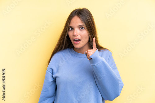 Young caucasian woman isolated on yellow background intending to realizes the solution while lifting a finger up