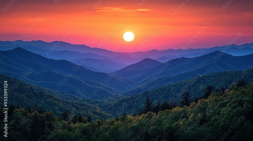 The sun is setting over the mountain range with trees in the foreground The sun is setting over the mountain range with trees in the foreground