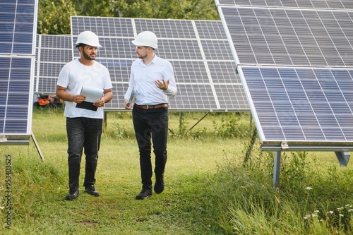 Solar power plant with two engineers walking and examining photovoltaic panels. Concept of alternative energy and its service