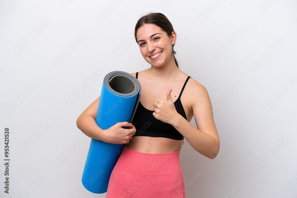 Young sport girl going to yoga classes while holding a mat isolated on white background giving a thumbs up gesture Young sport girl going to yoga classes while holding a mat isolated on white background giving a thumbs up gesture