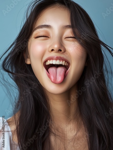 A woman with long hair is smiling and sticking out her tongue