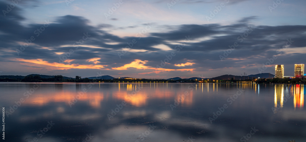Tranquil Sunset Reflections Over a Calm Lake with City Lights Tranquil Sunset Reflections Over a Calm Lake with City Lights