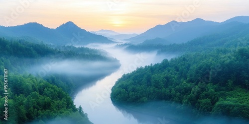 High angle view of a misty river in the valley between forested hills at dawn