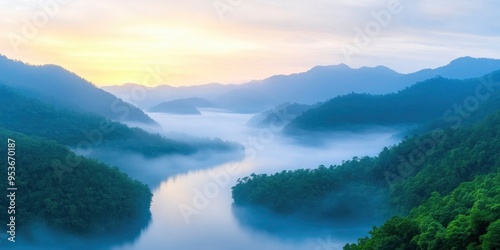 High angle view of a misty river in the valley between forested hills at dawn