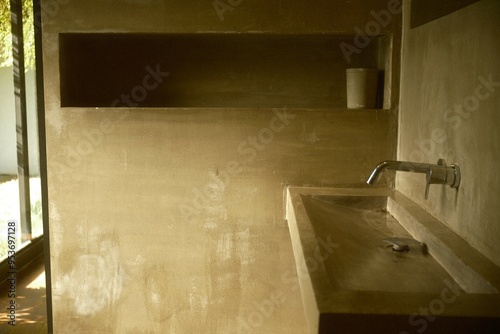 Industrial themed concrete bathroom design with a concrete sink, wall mounted faucet, and recessed shelf niches