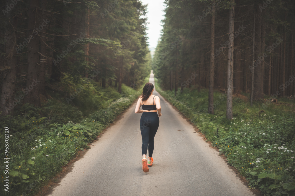 Brunette aged 20-25 in black sportswear running in nature in the evening sun. Active lifestyle. Outdoor sport
