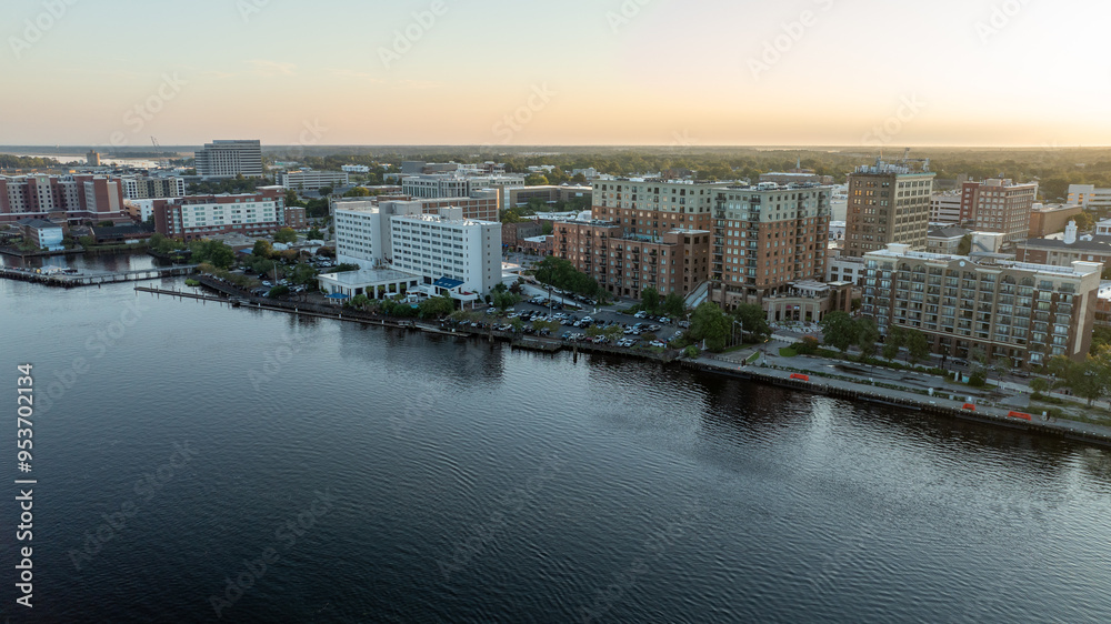 Fototapeta premium Aerial view of historic downtown Wilmington, NC, with buildings reflecting the sunrise over the Cape Fear River.