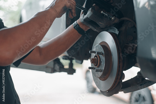 Close-up of a mechanic working on a car's brake system, showcasing the repair and maintenance of automotive components.