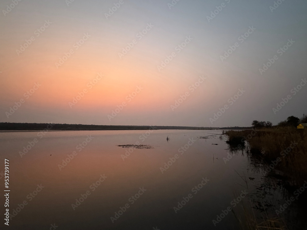 Blue and pink sky with reflection on the river, calm pink sunrise over the river in a safari Blue and pink sky with reflection on the river, calm pink sunrise over the river in a safari