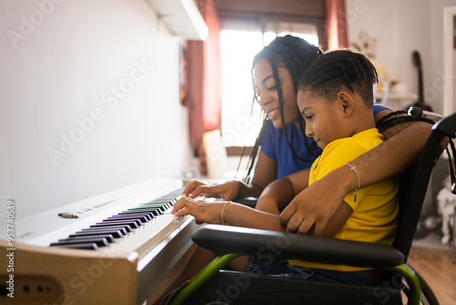 Two dark-skinned brothers play an electronic piano in their living room. The older sister hugs the little one as they play. Concept of young African people playing a piano. photo