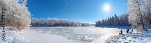 A serene winter landscape featuring a frozen lake surrounded by snow-covered trees under a clear blue sky.