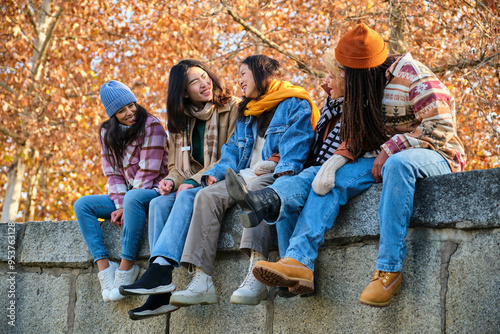 Obraz na płótnie Happy multi-ethnic group of young hipster diverse student friends having fun while hanging out sitting together outdoors. Friendship concept. w salonie