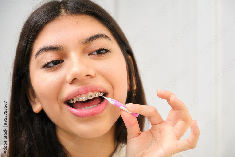 Female Latin teenager cleaning her braces with an interdental brush. Female Latin teenager cleaning her braces with an interdental brush.