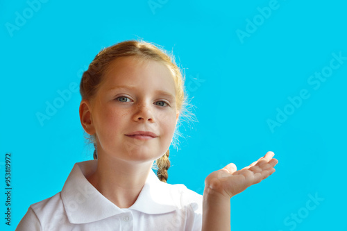 A sweet emotional girl with pigtails on a blue background in a white shirt. background for the design. a child's smile, happiness. Blue eyes.