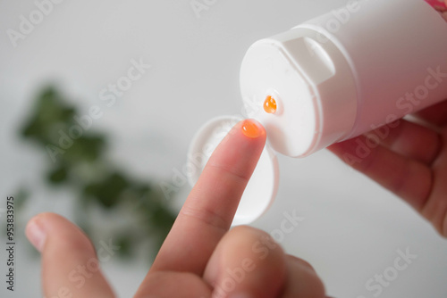 Woman squeezing orange gel onto her finger from a white tube