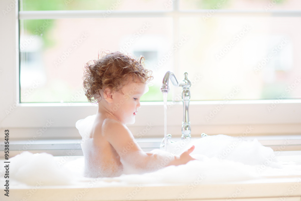 Naklejka premium Baby taking bath in kitchen sink