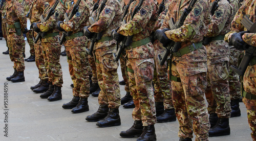 platoon of many army soldiers in camouflage uniform and assault rifle during parade and black boots photo