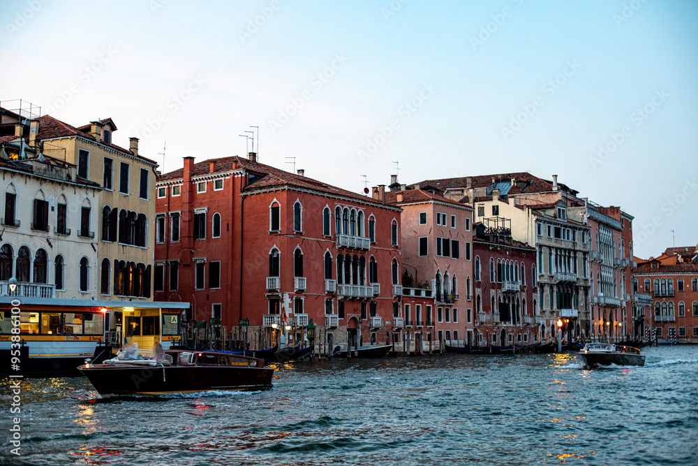 Scenic waterfront view of colorful buildings along a canal in Venice at sunset with boats cruising by Scenic waterfront view of colorful buildings along a canal in Venice at sunset with boats cruising by