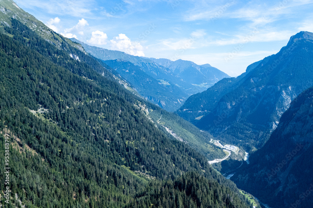 Breathtaking view of lush green valleys and majestic mountains in the Swiss Alps under a clear blue sky during summer Breathtaking view of lush green valleys and majestic mountains in the Swiss Alps under a clear blue sky during summer