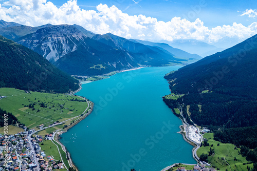 Aerial view of a turquoise lake surrounded by mountains and villages on a sunny day in the alpine region photo