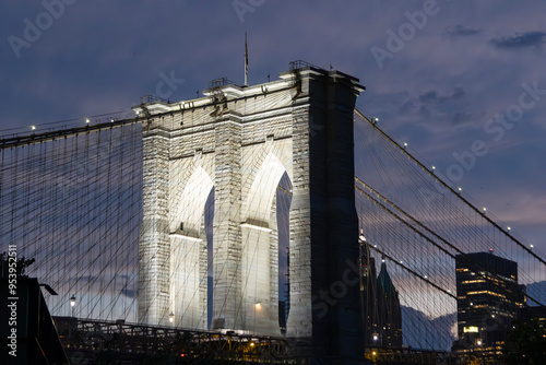 Brooklyn Bridge illuminated at twilight with New York City skyline in the backdrop showcasing vibrant lights and a colorful sunset