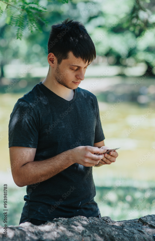 Fototapeta premium Young man using his smart phone in a peaceful park setting